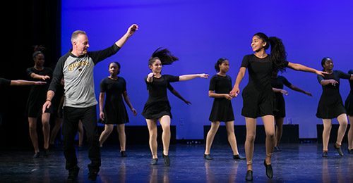 Dr. Martirano in a dance class on stage with students.